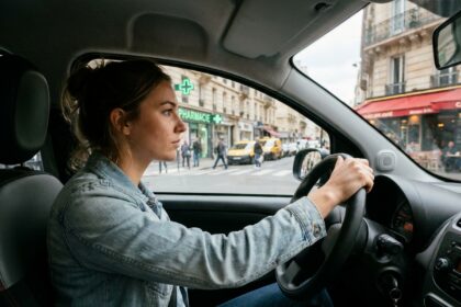Jeune conductrice débutante concentrée au volant dans un carrefour urbain animé