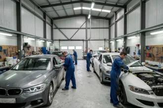 Vue d'ensemble d'un atelier de carrosserie automobile dans le Pas-de-Calais avec plusieurs véhicules en cours de réparation