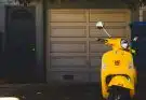 yellow motor scooter parked near white garage door