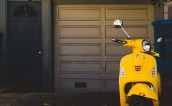 yellow motor scooter parked near white garage door