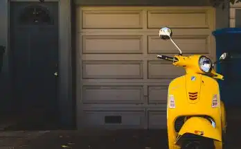 yellow motor scooter parked near white garage door